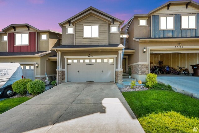 14483 S Ryegate Dr, Herriman, UT 84096 - view of front of property with stone siding, an attached garage, driveway, board and batten siding, and stucco siding