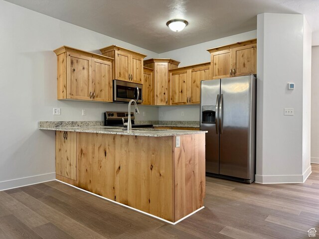 849 N Gleneagles Ct W, Tooele, UT 84074 - kitchen with stainless steel appliances, a peninsula, dark wood-style flooring, and light stone countertops