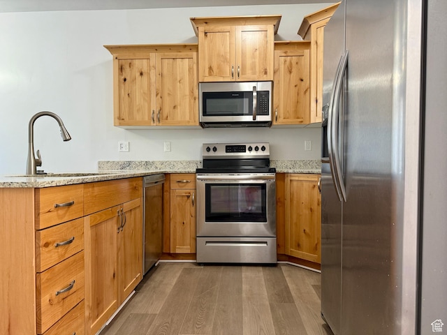 849 N Gleneagles Ct W, Tooele, UT 84074 - kitchen featuring stainless steel appliances, a peninsula, light wood-type flooring, light stone countertops, and light brown cabinetry