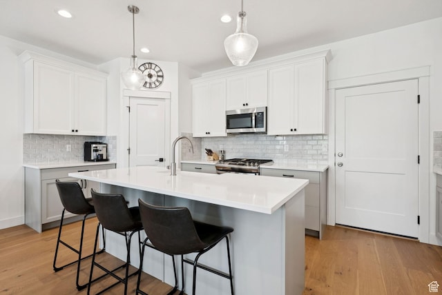 520 S Orchard Dr Unit 1, Bountiful, UT 84010 - kitchen with appliances with stainless steel finishes, backsplash, a breakfast bar area, light wood-style flooring, and recessed lighting