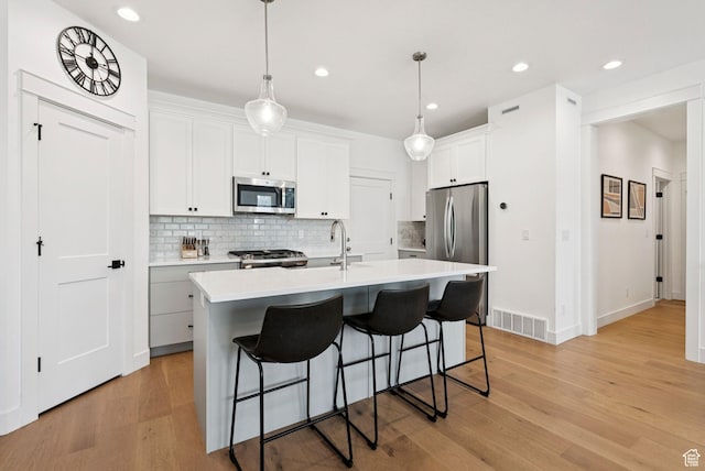 520 S Orchard Dr Unit 1, Bountiful, UT 84010 - kitchen with stainless steel appliances, backsplash, a kitchen breakfast bar, light wood finished floors, and recessed lighting