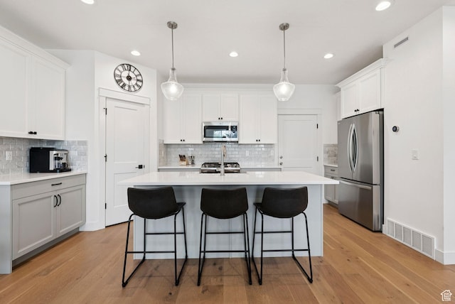 520 S Orchard Dr Unit 1, Bountiful, UT 84010 - kitchen with stainless steel appliances, a breakfast bar area, a center island with sink, backsplash, and light countertops