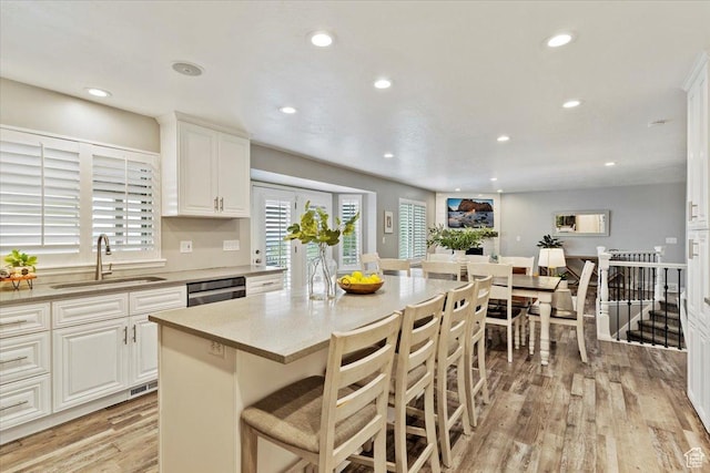 53 N Foxhill Rd N, North Salt Lake, UT 84054 - kitchen featuring light wood-type flooring, dishwasher, recessed lighting, a breakfast bar area, and white cabinets