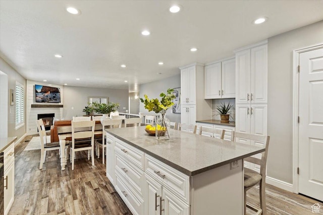 53 N Foxhill Rd N, North Salt Lake, UT 84054 - kitchen featuring wood finished floors, recessed lighting, a kitchen island, white cabinets, and a breakfast bar
