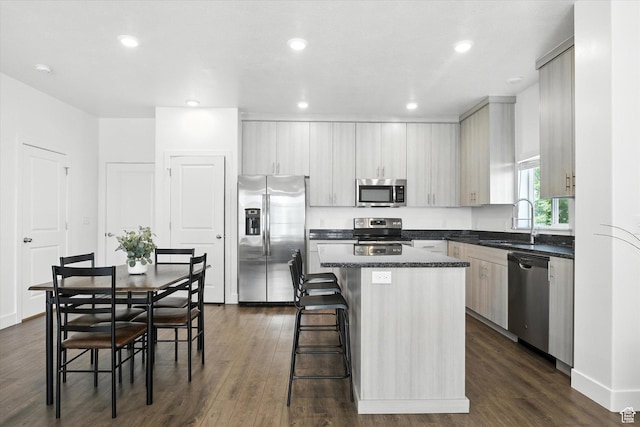 427 W 65 S, Providence, UT 84332 - kitchen with appliances with stainless steel finishes, a kitchen island, dark countertops, dark wood-style flooring, and a kitchen bar