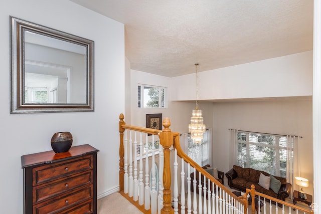 561 S Woodland Dr E, Farmington, UT 84025 - hall with an upstairs landing, a chandelier, carpet floors, and a textured ceiling