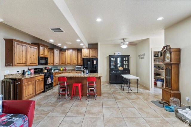 4257 W Lake Bridge Dr S, South Jordan, UT 84009 - kitchen with black appliances, brown cabinetry, light stone countertops, a kitchen bar, and recessed lighting