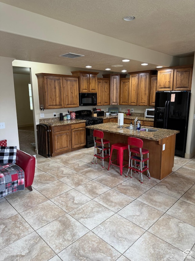 4257 W Lake Bridge Dr S, South Jordan, UT 84009 - kitchen featuring black appliances, brown cabinets, a center island with sink, recessed lighting, and stone counters