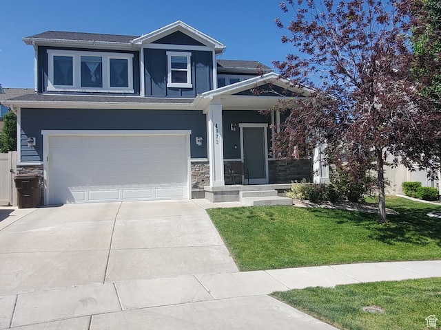4973 E Oakwood Dr, Eagle Mountain, UT 84005 - view of front of house featuring a front yard, driveway, stone siding, and a garage
