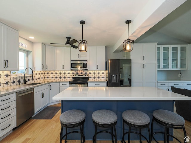 1402 E Valley Ridge Dr S, Sandy, UT 84093 - kitchen with stainless steel appliances, white cabinetry, backsplash, a kitchen bar, and light countertops