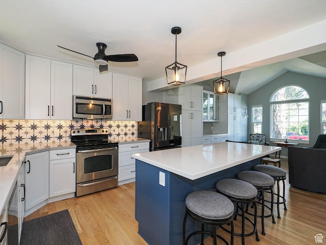 1402 E Valley Ridge Dr S, Sandy, UT 84093 - kitchen featuring appliances with stainless steel finishes, a breakfast bar, light wood finished floors, white cabinets, and vaulted ceiling