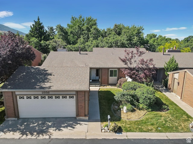 2556 E 1980 N, Layton, UT 84040 - view of front facade with brick siding, driveway, roof with shingles, an attached garage, and a front lawn