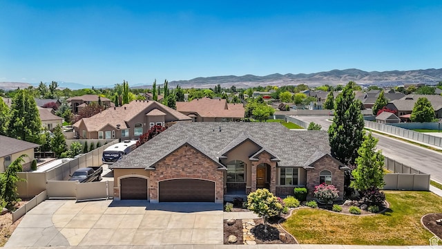 3179 W Hayden Ridge Way S, Riverton, UT 84065 - view of front facade featuring a garage, concrete driveway, a residential view, stone siding, and a mountain view