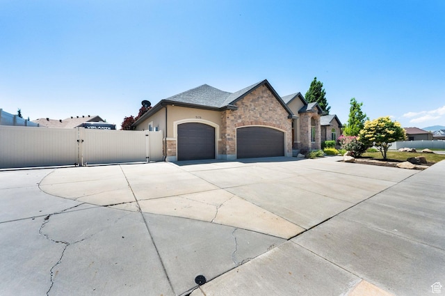 3179 W Hayden Ridge Way S, Riverton, UT 84065 - view of front facade with a gate, an attached garage, driveway, stone siding, and stucco siding