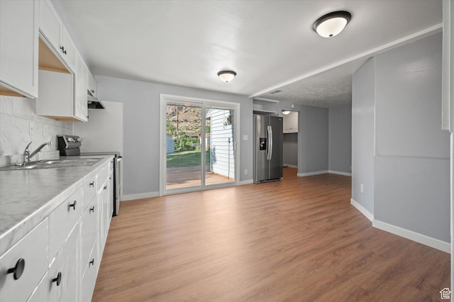 1302 E Harrop S, Ogden, UT 84404 - kitchen with stainless steel appliances, decorative backsplash, light wood-type flooring, white cabinets, and light countertops