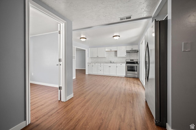1302 E Harrop S, Ogden, UT 84404 - kitchen with stainless steel appliances, white cabinetry, wood finished floors, light countertops, and under cabinet range hood