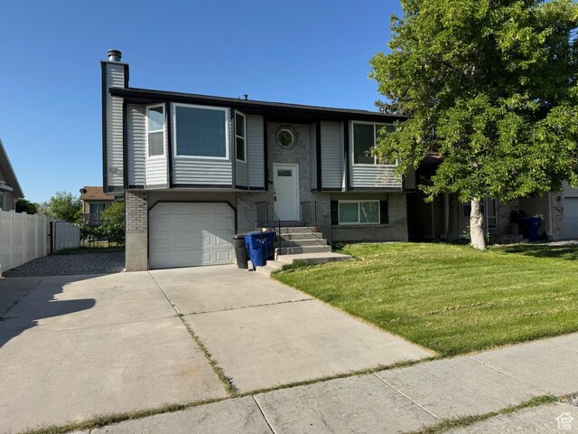 3923 W 5820 S, Taylorsville, UT 84118 - split foyer home with concrete driveway, a chimney, brick siding, and a garage