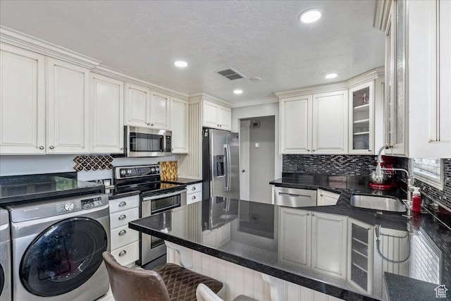 104 E 650 N, Bountiful, UT 84010 - kitchen with appliances with stainless steel finishes, washer and clothes dryer, a kitchen breakfast bar, a peninsula, and glass insert cabinets