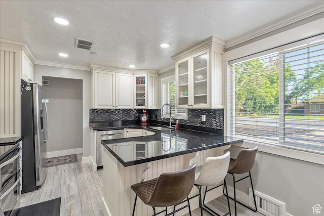 104 E 650 N, Bountiful, UT 84010 - kitchen with appliances with stainless steel finishes, a peninsula, backsplash, crown molding, and a kitchen breakfast bar