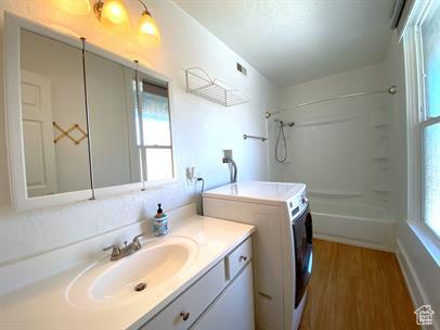 1309 E Hidden Creek Ct S, Holladay, UT 84117 - full bath with vanity, washtub / shower combination, wood finished floors, and separate washer and dryer