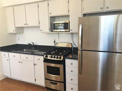 1309 E Hidden Creek Ct S, Holladay, UT 84117 - kitchen with stainless steel appliances, dark wood finished floors, dark countertops, and white cabinets