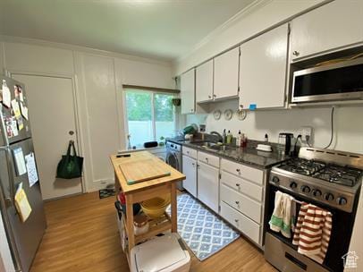 1309 E Hidden Creek Ct S, Holladay, UT 84117 - kitchen featuring stainless steel appliances, dark countertops, light wood-style flooring, white cabinets, and crown molding