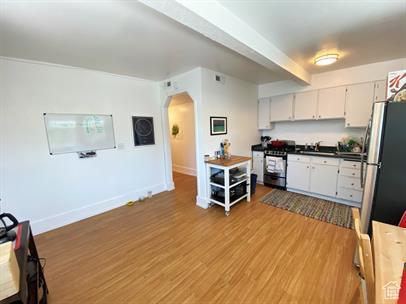 1309 E Hidden Creek Ct S, Holladay, UT 84117 - kitchen with stainless steel appliances, arched walkways, white cabinets, light wood finished floors, and dark countertops