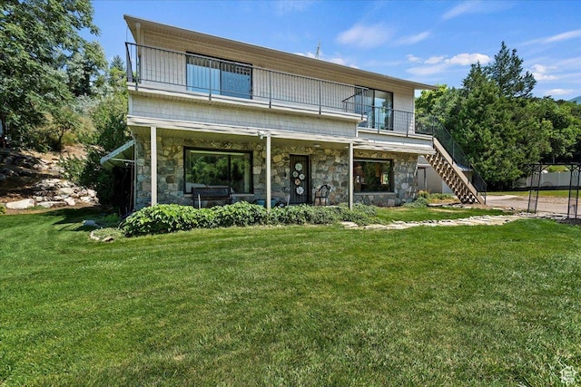 2391 Kays Creek Dr, Layton, UT 84040 - view of front of home with stone siding, a balcony, stairs, and a front lawn