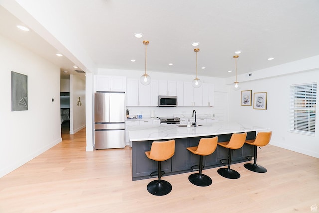 357 W Posies Dr, Garden City, UT 84028 - kitchen with stainless steel appliances, light wood finished floors, white cabinetry, a center island with sink, and recessed lighting