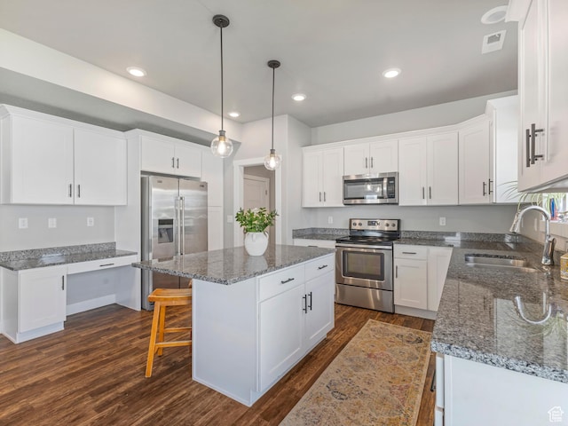 3187 N 3450 W, Plain City, UT 84404 - kitchen featuring appliances with stainless steel finishes, dark wood-type flooring, a center island, white cabinetry, and dark stone countertops