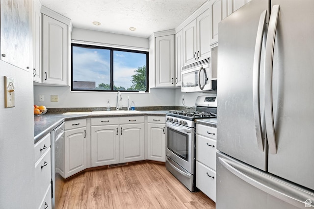 632 S 1150 W, Layton, UT 84041 - kitchen featuring stainless steel appliances, white cabinets, dark countertops, light wood-style flooring, and a textured ceiling