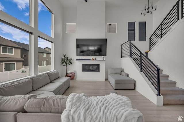 12357 S Eovaldi Ave, Herriman, UT 84096 - living room featuring a towering ceiling, stairway, a glass covered fireplace, and wood finished floors