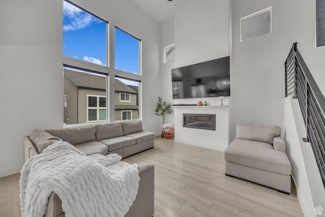12357 S Eovaldi Ave, Herriman, UT 84096 - living area with a towering ceiling, a glass covered fireplace, and light wood-style flooring