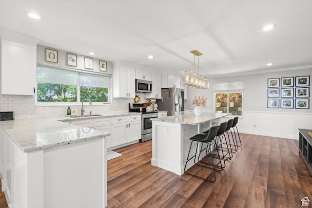 958 N Main St W, Farmington, UT 84025 - kitchen with appliances with stainless steel finishes, white cabinets, dark wood-type flooring, a breakfast bar, and ornamental molding