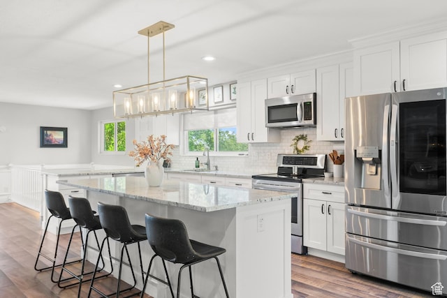 958 N Main St W, Farmington, UT 84025 - kitchen featuring appliances with stainless steel finishes, a center island, tasteful backsplash, white cabinetry, and dark wood-style flooring