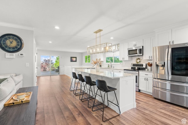 958 N Main St W, Farmington, UT 84025 - kitchen featuring appliances with stainless steel finishes, a breakfast bar, white cabinetry, a center island, and open floor plan