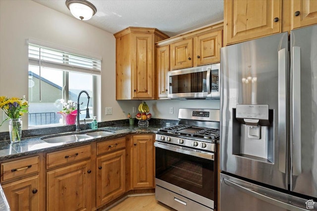 2876 S 1200 W, Syracuse, UT 84075 - kitchen with appliances with stainless steel finishes, dark stone countertops, light wood-type flooring, and a textured ceiling