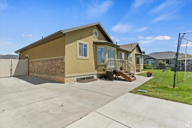 2876 S 1200 W, Syracuse, UT 84075 - view of home's exterior with stucco siding, stone siding, a patio, and a gate
