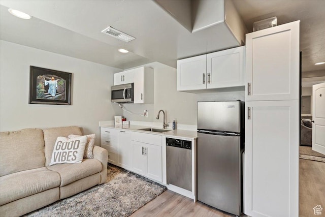 2876 S 1200 W, Syracuse, UT 84075 - kitchen featuring appliances with stainless steel finishes, light wood-type flooring, open floor plan, white cabinetry, and recessed lighting