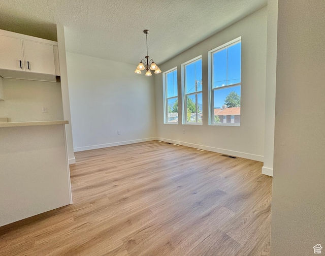 1650 N Main St N Unit 116, Layton, UT 84041 - unfurnished dining area with light wood-type flooring, a chandelier, and a textured ceiling