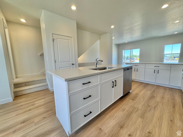 1650 N Main St N Unit 116, Layton, UT 84041 - kitchen featuring stainless steel dishwasher, light wood-type flooring, an island with sink, a textured ceiling, and white cabinetry