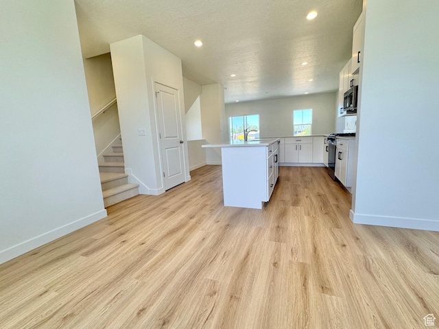 1650 N Main St N Unit 116, Layton, UT 84041 - kitchen with range with gas cooktop, stainless steel microwave, white cabinetry, light wood finished floors, and light countertops