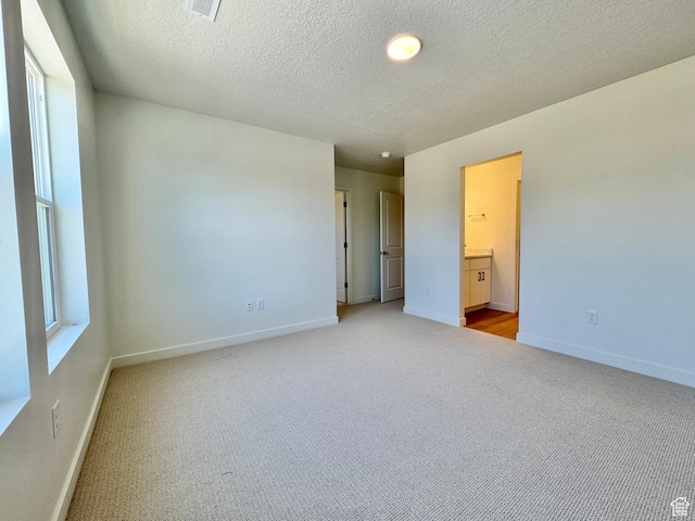 1650 N Main St N Unit 116, Layton, UT 84041 - unfurnished bedroom featuring light carpet, a textured ceiling, and connected bathroom