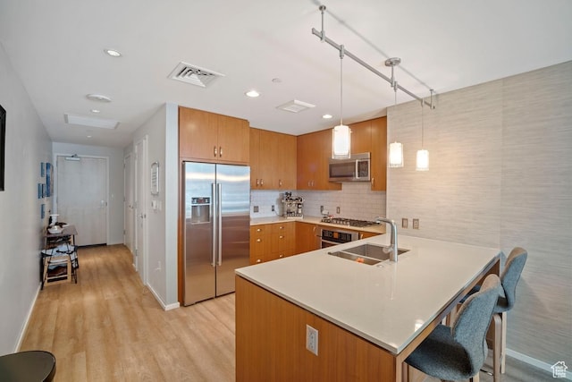 35 E 100 S Unit 708, Salt Lake City, UT 84111 - kitchen featuring appliances with stainless steel finishes, a peninsula, brown cabinetry, light countertops, and light wood-type flooring