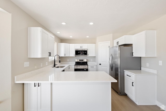 1919 E Church Way, Eagle Mountain, UT 84005 - kitchen featuring appliances with stainless steel finishes, light wood-style floors, a peninsula, light countertops, and white cabinetry