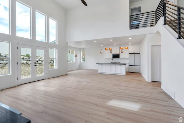 7625 N Silver Creek Way, Eagle Mountain, UT 84005 - unfurnished living room featuring a high ceiling, plenty of natural light, light wood finished floors, stairway, and recessed lighting