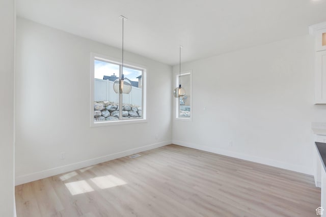 7625 N Silver Creek Way, Eagle Mountain, UT 84005 - unfurnished dining area with light wood-style flooring and baseboards