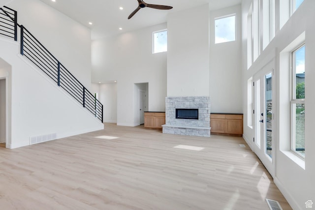 7625 N Silver Creek Way, Eagle Mountain, UT 84005 - unfurnished living room with a towering ceiling, a stone fireplace, light wood-style flooring, ceiling fan, and recessed lighting