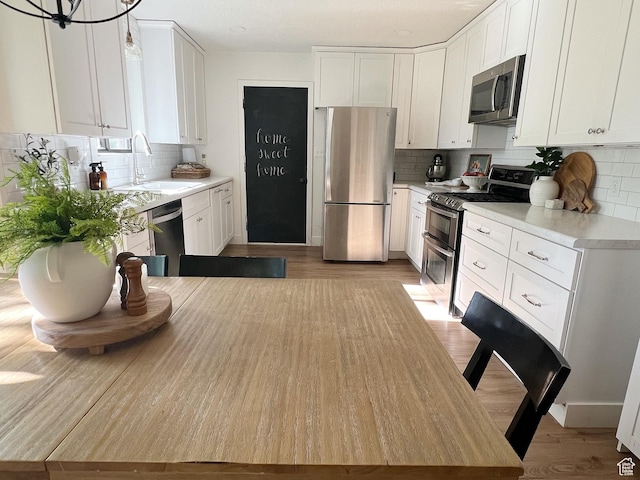 920 S 940 W, Richfield, UT 84701 - kitchen featuring appliances with stainless steel finishes, decorative backsplash, white cabinetry, and light wood-style floors