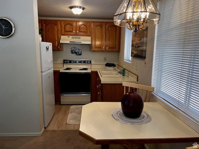 840 N Twin Lakes Dr Unit 225, St George, UT 84770 - kitchen featuring white appliances, custom exhaust hood, a chandelier, light countertops, and brown cabinets